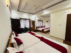 a hotel room with three beds and a mirror at Homey - vythiri bus station in Vythiri