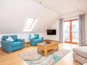 a living room with two blue chairs and a coffee table at The Hive in Dornoch