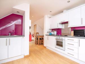 a kitchen with white cabinets and purple accents at The Hive in Dornoch +9 photos