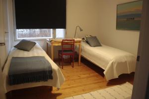two beds in a room with a desk and a chair at Cozy Summerhouse by the River with free BIKES and ping pong in Rovaniemi