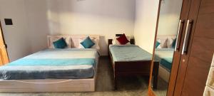 a small bedroom with two beds and a mirror at Elephant County Resort in Masinagudi
