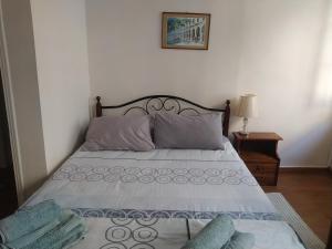 a bed with two pillows and a picture on the wall at Spiros old town apartment in Corfu