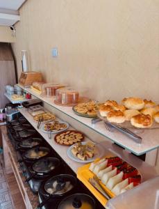 a buffet line with many different types of bread and pastries at Pousada Praia Dos Encantos in Japaratinga