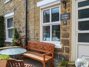 a wooden bench sitting outside of a coffee shop at Squirrel Cottage in Filey