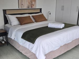 a large bed with white sheets and brown pillows at 511 Umdloti Resort 1 bed beachfront Apartment self catering Great Sea View in Umdloti +45 photos