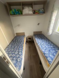 two beds in a small room with a window at mobilhome 5 personnes in Saint-Arnoult