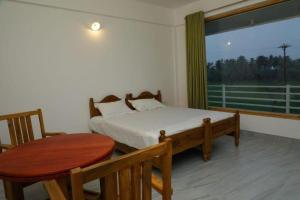 a bedroom with a bed and a table and a window at MJ paddy view Homestay in Kumarakom