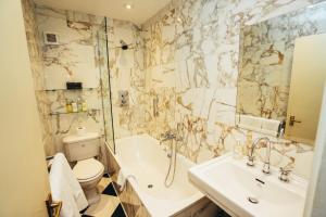 a bathroom with a toilet and a tub and a sink at The Peacock at Rowsley in Great Rowsley