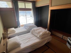 two twin beds in a room with a window at Togari Sunshine Lodge in Iiyama