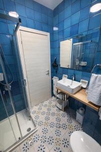 a blue tiled bathroom with a sink and a shower at Soleil Apartment - Zona Ospedale Pederzoli in Peschiera del Garda