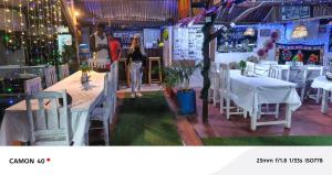 a woman walking through a restaurant with tables and chairs at Piscine bimoko in Nosy Be
