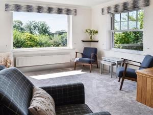 a living room with a couch and a table and two windows at Repentance View in Carrutherstown