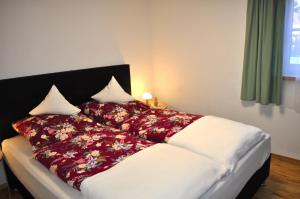 a bed with a red and white blanket on it at Ferienwohnung Baumgartner in Bad Hindelang