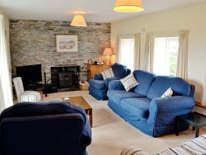 a living room with blue couches and a fireplace at Tregunna Cottage in Wadebridge