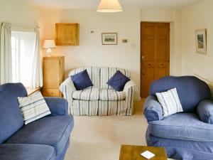 a living room with two blue chairs and a couch at Tregunna Cottage in Wadebridge +12 photos