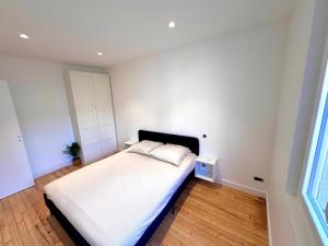 a bedroom with a bed with white sheets and a window at Appartement Toulouse - Quartier des Chalets in Toulouse