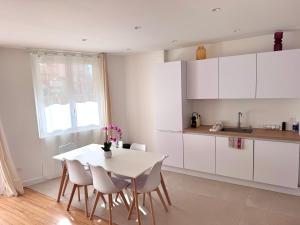 a white kitchen with a white table and chairs at Appartement Toulouse - Quartier des Chalets in Toulouse
