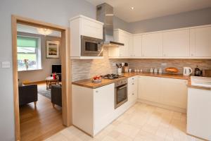 a kitchen with white cabinets and a living room at Fall in Green in Haworth
