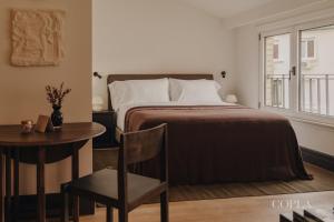 a bedroom with a bed and a table and a window at Copla Bilbao in Bilbao