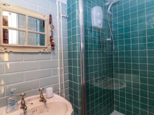 a bathroom with a green tiled shower and a sink at Sammy Hakes Cottage in Watchet +12 photos
