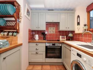 a kitchen with white cabinets and a dishwasher at Sammy Hakes Cottage in Watchet