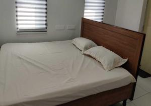 a bed with a wooden headboard and two pillows at Kostha Suites in Anumalkudūru