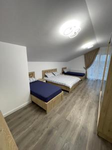 two beds in a room with wooden floors at Rădăuți Residence 3 in Rădăuţi