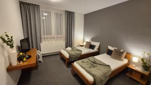 a hotel room with two beds and a television at Penzion Jelínek in Opočno