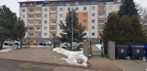 a apartment building with a fence and snow in front of it at Apartman Zvolen in Zvolen