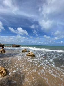 a person standing on a beach with rocks in the water at Suíte na praia do amor in Conde