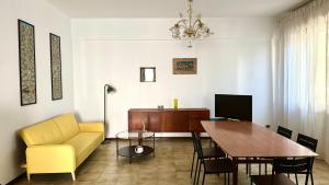 a living room with a dining room table and a yellow chair at N294 - Numana, ampio quadrilocale con giardino e wifi in Numana