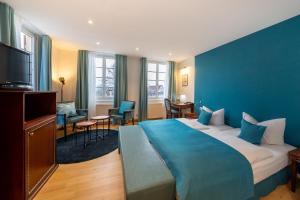 a hotel room with a large bed with a blue wall at Hotel Am Schloss *** Superior in Tübingen +108 photos