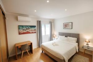 a bedroom with a white bed and a desk and a window at Home In Green Caldera in Furnas