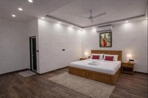 a bedroom with a large bed with red pillows at Mud Meadows Peace and Tranquility Farm With Pool in Faridabad