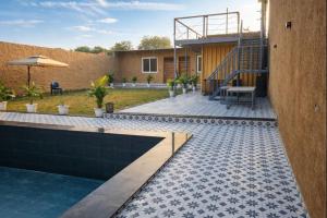 a backyard with a pool and a table and an umbrella at Mud Meadows Peace and Tranquility Farm With Pool in Faridabad