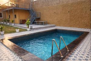 a swimming pool with two metal rails in a building at Mud Meadows Peace and Tranquility Farm With Pool in Faridabad +23 photos