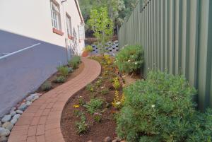a brick walkway next to a building with flowers at Naval Hill Nook in Bloemfontein