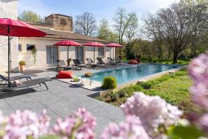 a house with a swimming pool with umbrellas at Domaine de la Bedosse in Alès