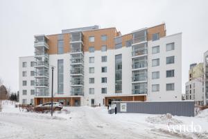 an apartment building in the snow in front of a street at LuxHOMES Studio in Tapiola in Espoo