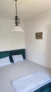 a white bed with two pillows and a light fixture at Apartman Biser in Trebinje