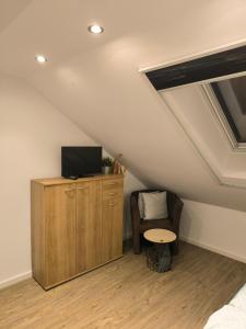 a attic room with a tv and a chair and a table at Helle Wohnung mit zwei Schlafzimmern in Eching