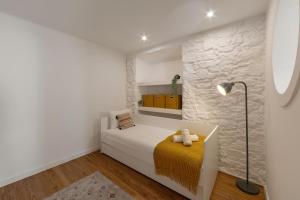 a white bedroom with a bed and a lamp at The Bliss House in Lourinhã