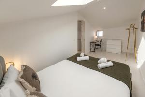a white bedroom with a large bed with towels on it at The Bliss House in Lourinhã