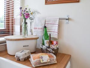 eine Theke mit einer Blumenvase und einer Flasche Wein in der Unterkunft Swallows Barn in Dallington