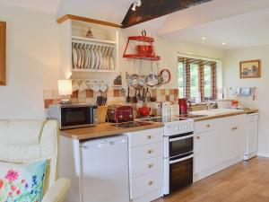 eine Küche mit weißen Schränken und einem Herd mit Backofen in der Unterkunft Swallows Barn in Dallington