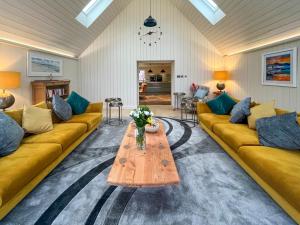 a living room with yellow couches and a wooden table at Achandoilach House in Strathcarron