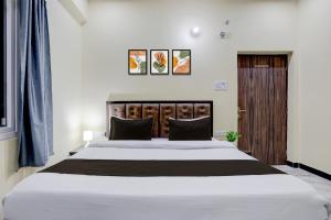 a bedroom with a large white bed with a wooden headboard at Hotel O by OYO SGD Lawn And Hotel in Varanasi