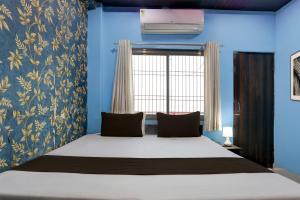 a bedroom with a bed with blue walls and a window at Hotel O by OYO Shree Paying Guest House in Varanasi