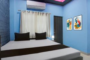 a bedroom with a bed with blue walls and a window at Hotel O by OYO Shree Paying Guest House in Varanasi