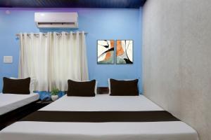 two beds in a room with blue walls and curtains at Hotel O by OYO Shree Paying Guest House in Varanasi